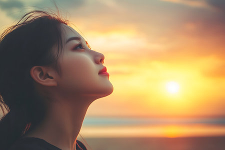Beautiful asian woman face on the beach with sunset sky backgroundの素材