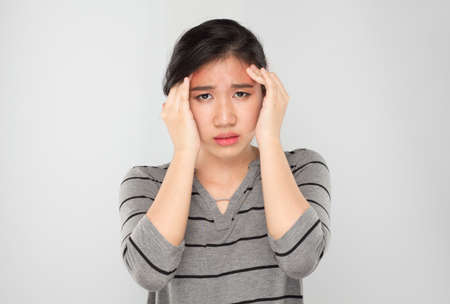 young asian woman arms raised touch her head feel headacheの写真素材