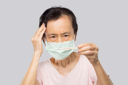 old asian woman check thermometer after her feel fever and sick