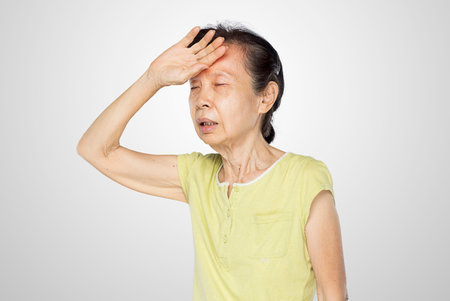 old asian woman touched her forehead feel fever and sick in white backgroundの写真素材