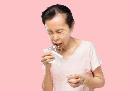old asian woman due to cough spread saliva and sore throatの写真素材