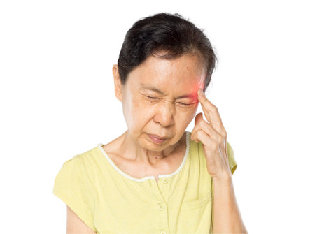 old asian woman arms raised touch her head feel headacheの写真素材