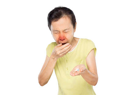 old asian woman due to cough spread saliva and holding pills on white backgroundの写真素材