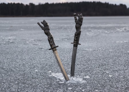 Knives in ice at the river freezeの写真素材