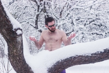 Naked wild man in the winter snowy cold forestの写真素材