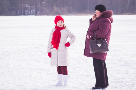 Zhytomyr, Ukraine - January 19, 2016: Girl looking forward and granny talking on phone at winterのeditorial素材