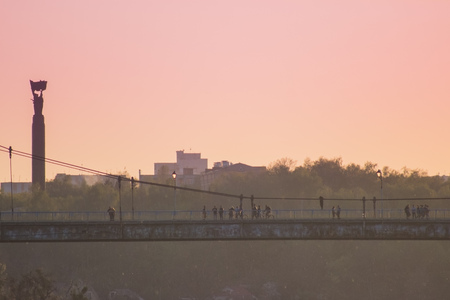 silhouette of people traveling across the bridge in the eveningの写真素材