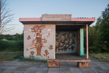 Rural bus stop shelter with wheat field and village background.の写真素材