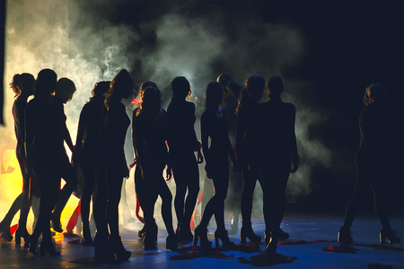 silhouettes of dance crowd in front of bright stage lightsの写真素材