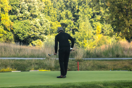 Man playing a game of golf by his cart near lakeの写真素材