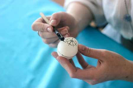 Cute little child girl painting with blue and yellow colors Easter eggs