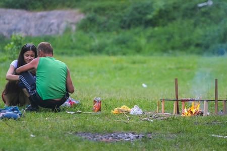 Zhytomyr, Ukraine - May 25, 2015: Couple on picnic setting with burning fire at summerのeditorial素材