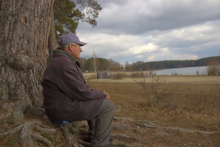 Zhytomyr, Ukraine - October 15, 2015: Portrait of a wise old man sitting under tree in the autumn forestのeditorial素材