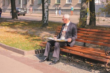Zhytomyr, Ukraine - September 05, 2015: senior man reading on a bench like famous film actor forest jumpのeditorial素材