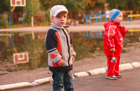Zhytomyr, Ukraine - September 25, 2015: a boy in a raincoat after rain look at cameraのeditorial素材