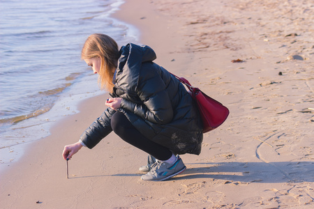 Zhytomyr, Ukraine - September 05, 2015: girl draws a sun in the sand on the beachのeditorial素材