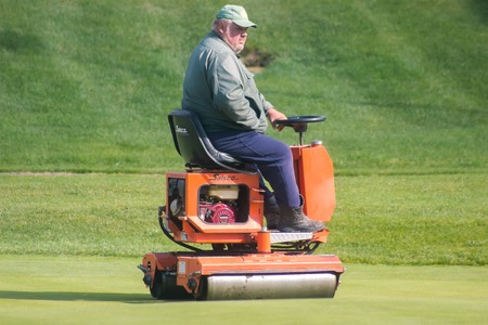 Zhytomyr, Ukraine - May 12, 2016: Big fat man gardening grass with a brushcutter at golf fieldのeditorial素材