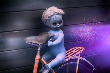 Scary ghost plastic doll with black tears at bicycle on mystic night nature background photo.の写真素材