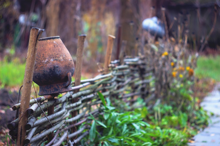 Clay jug on a fence. Rural scenery, traditional old clay pots on a wattled fence.の写真素材