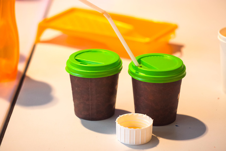 two brown paper cups for coffee with a straw and a green lidの写真素材