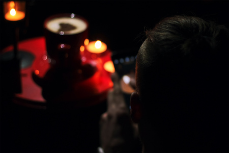 Man watching on cup of brewed coffee with painted heart, a branch of spruce, candles and lanternの写真素材