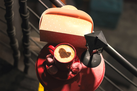 Cup of brewed coffee with painted heart, a branch of spruce and lanternの写真素材