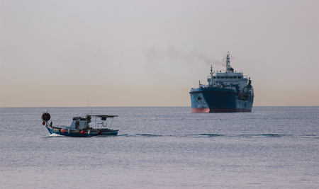 Calm sea, breakwater, and ships on the horizon