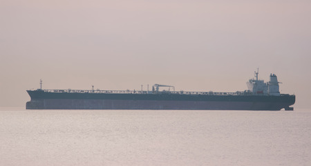 Calm sea, breakwater, and ships on the horizon