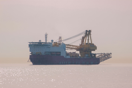 Calm sea, breakwater, and ships on the horizonの写真素材