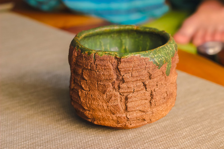 Handmade empty pottery tea bowl brown in hands