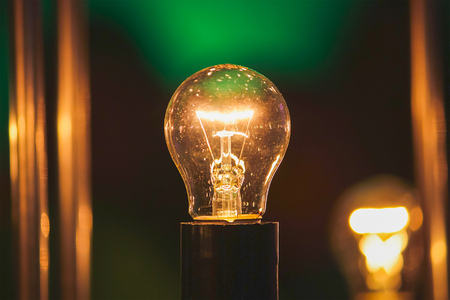 glowing white light bulb against blue wall backgroundの写真素材