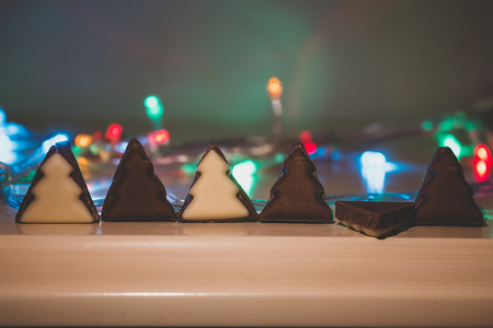 Christmas tree chocolate shapes on wooden table at garland blurred backgroundの写真素材