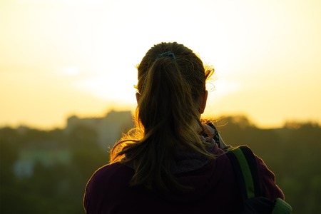 Silhouette of a girl taking pictures of the sunrise