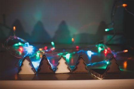 Christmas tree chocolate shapes on wooden table at garland blurred backgroundの写真素材