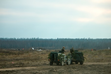 Military patrol car on a field. Army war concept. Armored vehicle with gun in action. Decorated.の写真素材