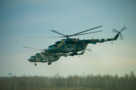 Helicopter in the flight at sunset above war field