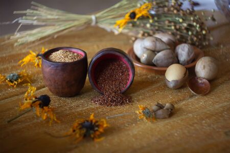 Composition of flax, sesame and avocado seeds in banks at yellow flowers background