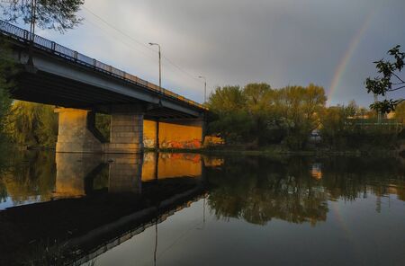 The view from below looks up. Rainbow with trees covering at bridge and river landscape