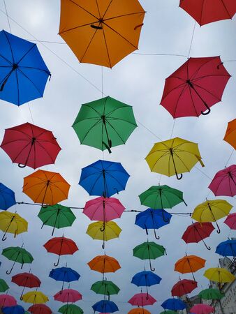 Colorful umbrellas background. Colorful umbrellas in the cloudy sky. Street decoration.の写真素材