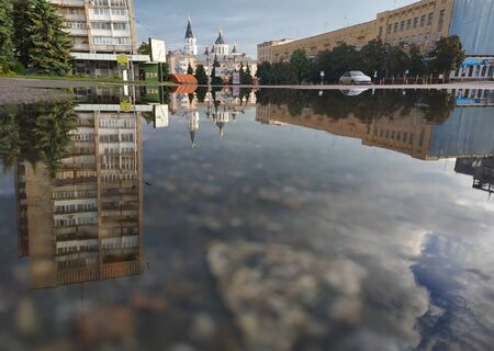 City in the morning, looking into a street canyon with sunlight and reflection in a puddle on the streetの写真素材