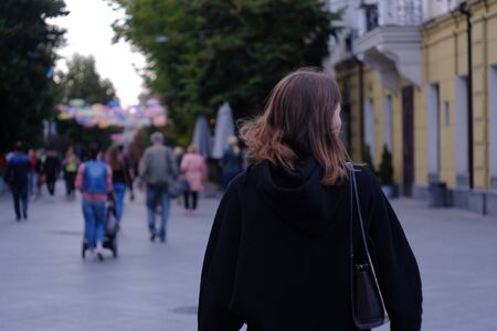 Portrait of young woman walking in the street view from behind.の写真素材
