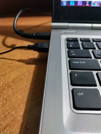 inserting USB cable into laptop on desktop workplace backgroundの写真素材