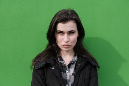 Young caucasian girl with brown hair posing on green wall background.の写真素材
