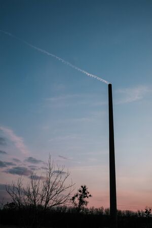 Electric pole with chemical smoke trails from airplane in the sky. Beautiful evening clouds...