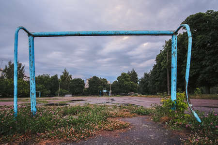 Abandoned soccer field and old rusty goals on sunset, nostalgia concept.