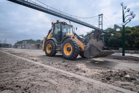 Excavator at reconstruction coastal structures, construction of quay at small townの写真素材