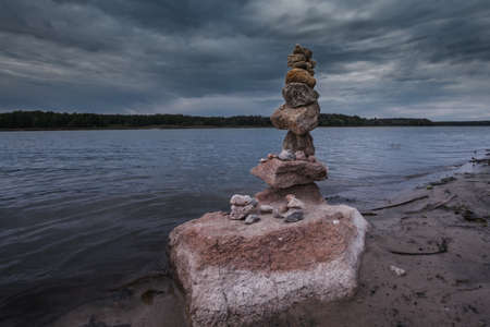 Stone arrange in balance in the bank of the river with dramatic cloudy sky.の写真素材