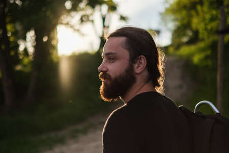 Side view of young bearded male hiker looking away while standing in autumn countrysideの写真素材
