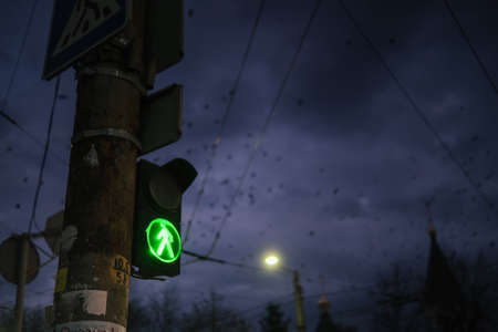 Rusty pedestrian traffic light showing green in the nightの写真素材