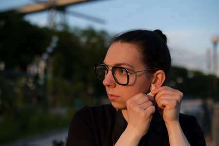 Woman outdoor wearing earrings. Portrait of woman in glasses at sunset.